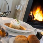 Vihulan kartanon päärakennuksen ravintolan ruoka-annos taustalla takkatuli