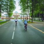 Kaksi naista ajamassa pyörällä Pärnussa, Hedon Span edustalla. Kesäinen kuva.