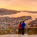 Pariskunta katsomassa Bergenin kaupunkia auringonlaskun aikaan Floyen vuorelta