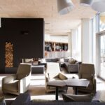 Hotellin aula, jossa harmaat nojatuolit ja takka, jonka kyljessä halkopino