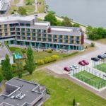 Hotellirakennus meren äärellä, jonka edessä kaksi padel kenttää.