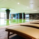 Vihreä uima-allas ja lepotuoli hotellin allasosastolla