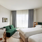 Hotellihuone kahdella erillisellä vuoteella ja vihreällä sohvalla