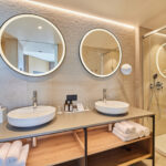 Kylpyhuone kahdella lavuaarilla ja kahdella pyöreällä peilillä