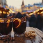 Glögilasit puupöydällä, taustalla tunnelmalliset joulutorivalot.