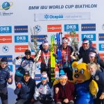 Pariviestin pronssijuhlat podiumilla, Suvi Minkkinen ja Tero Seppälä sekä valmennus- ja huoltotiimiä, Ampumahiihdon maailmancup Otepää 2026 📷 Anita Kantola